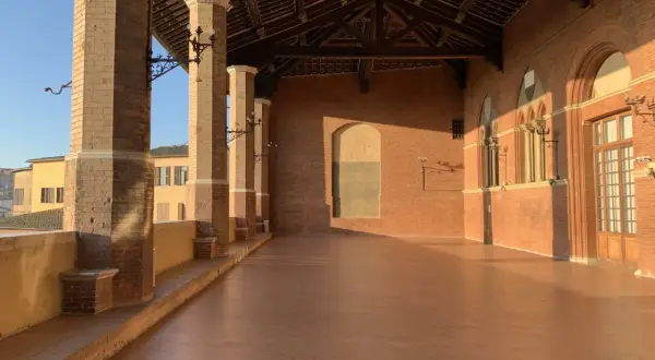 La loggia dei Nove a Siena, con le sue colonne in cotto e il tetto a capriate, baciata dalla luce dorata del tramonto.