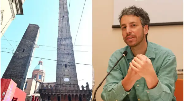 Le torri Asinelli e Garisenda a Bologna, con una cupola in mezzo, e un uomo che parla al microfono.