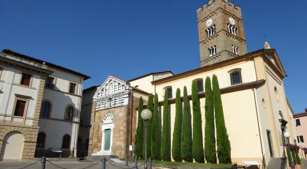 Piazza ad Altopascio dove si trova la chiesa con campanile medievale e cipressi slanciati.