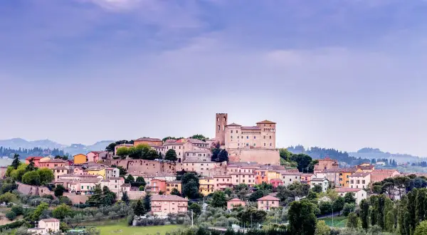 Borgo medievale arroccato sulla collina nella valle del Rubicone, con un imponente castello e case colorate.