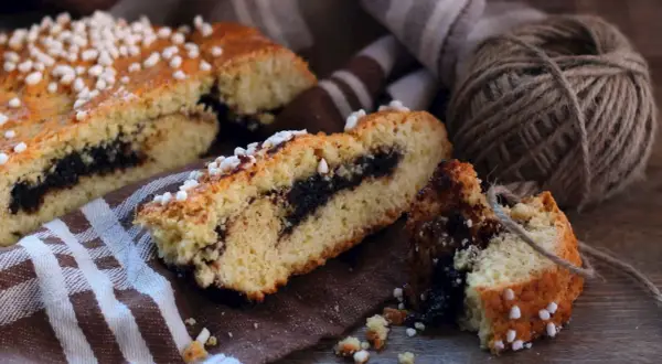 Fette di dolci emiliani con ripieno scuro, guarnite con zuccherini, su un tovagliolo a righe.