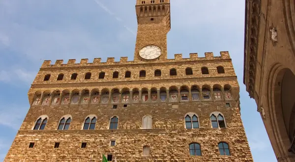 Palazzo Vecchio, simbolo di Firenze medievale, con la sua torre imponente e gli stemmi araldici.