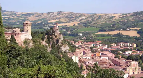Un borgo medievale con un castello domina il paesaggio collinare di Brisighella, Italia.
