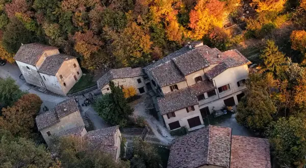 Borgo autunnale a Montale PT, Italia, con case in pietra e tetti in cotto immerse nel foliage colorato.
