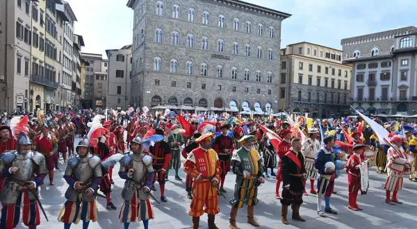 Sfilata storica a San Giovanni, Firenze. Uomini in costume rinascimentale, con armature e bandiere, celebrano la festa.