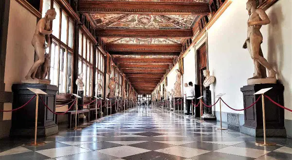 Corridoio degli Uffizi con statue classiche e soffitto affrescato. Un assaggio di cosa vedere agli Uffizi, tra capolavori e architettura.