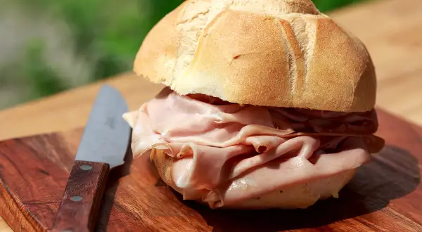 Panino con mortadella su tagliere di legno, un'ottima idea per sapere dove fermarsi tra Bologna e Firenze.