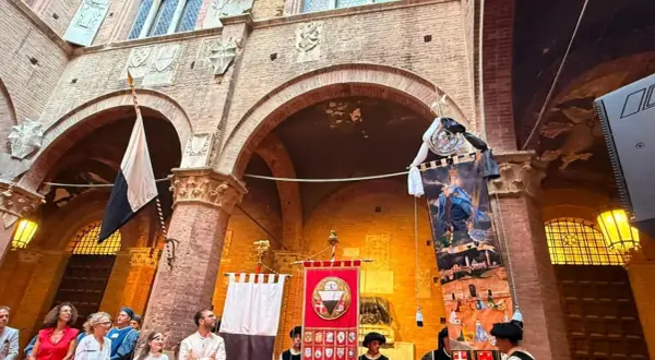 Sfilata storica a Siena con stendardi e costumi d'epoca, evocando l'atmosfera del Palio.