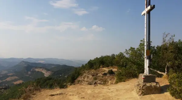 Croce in cima a un crinale roccioso, con un panorama mozzafiato sulle montagne dell'Emilia Romagna.