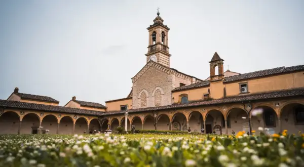 Cortile con portico ad archi e campanile, immerso in un prato fiorito. Un luogo sereno sul monte Senario.
