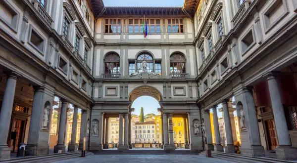 Cortile degli Uffizi, uno dei principali musei da vedere a Firenze. Architettura rinascimentale con statue e un arco che si apre sulla città.