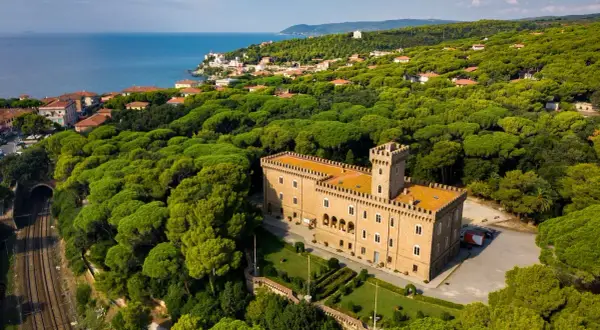 Castiglioncello cosa vedere: un castello imponente circondato da una pineta rigogliosa, con il mare all'orizzonte.