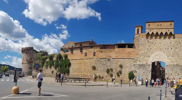 La **Siena Fortezza Medicea** domina il paesaggio con le sue mura imponenti. Turisti passeggiano sotto il sole, ammirando la storia.