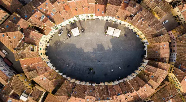 Vista aerea della **Piazza Anfiteatro** di Lucca, con i suoi caratteristici edifici ovali e i tetti rossi che la circondano.