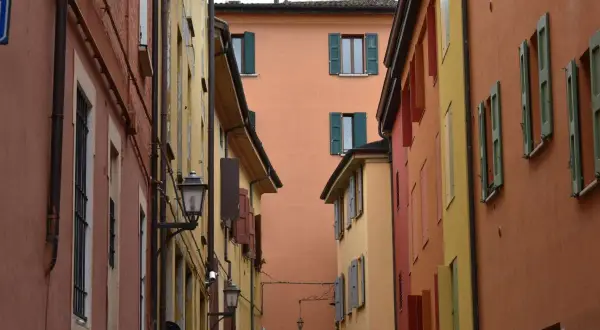 Vicoli colorati, perfetti per gite fuori porta da Bologna. Case con persiane verdi e lampioni antichi creano un'atmosfera suggestiva.