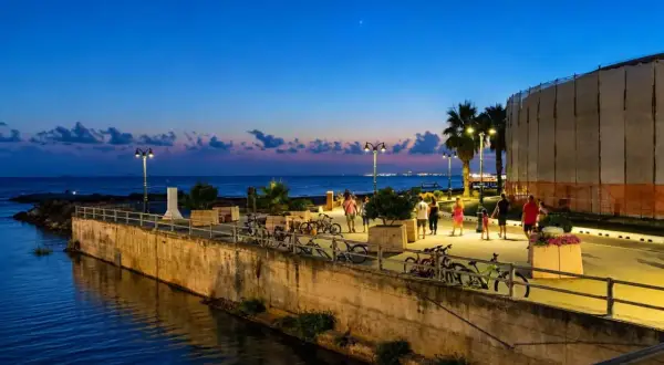 Passeggiata serale lungo il mare a Follonica, con persone che camminano e biciclette parcheggiate.
