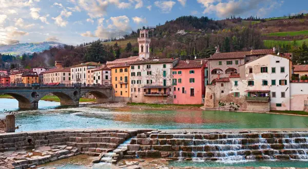 Il **parco fluviale Santa Sofia** con case colorate affacciate sul fiume e un ponte ad archi.