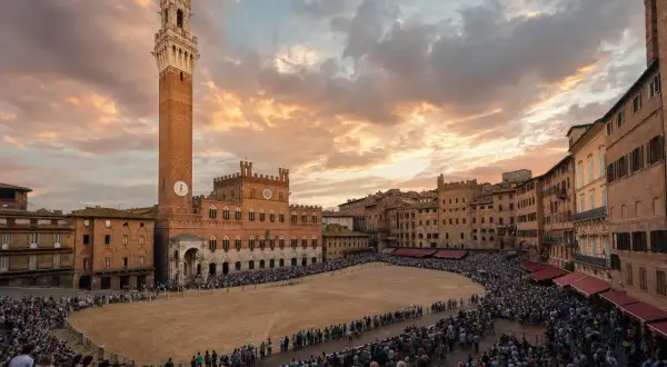 Piazza del Campo a Siena, gremita di spettatori in attesa del Palio. Cos'è il Palio di Siena? Una corsa di cavalli storica.