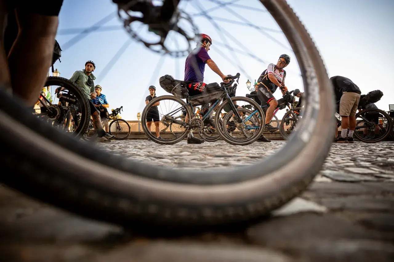 Ciclisti pronti per nuovi itinerari in bici, con le ruote in primo piano che promettono avventura su strade acciottolate.