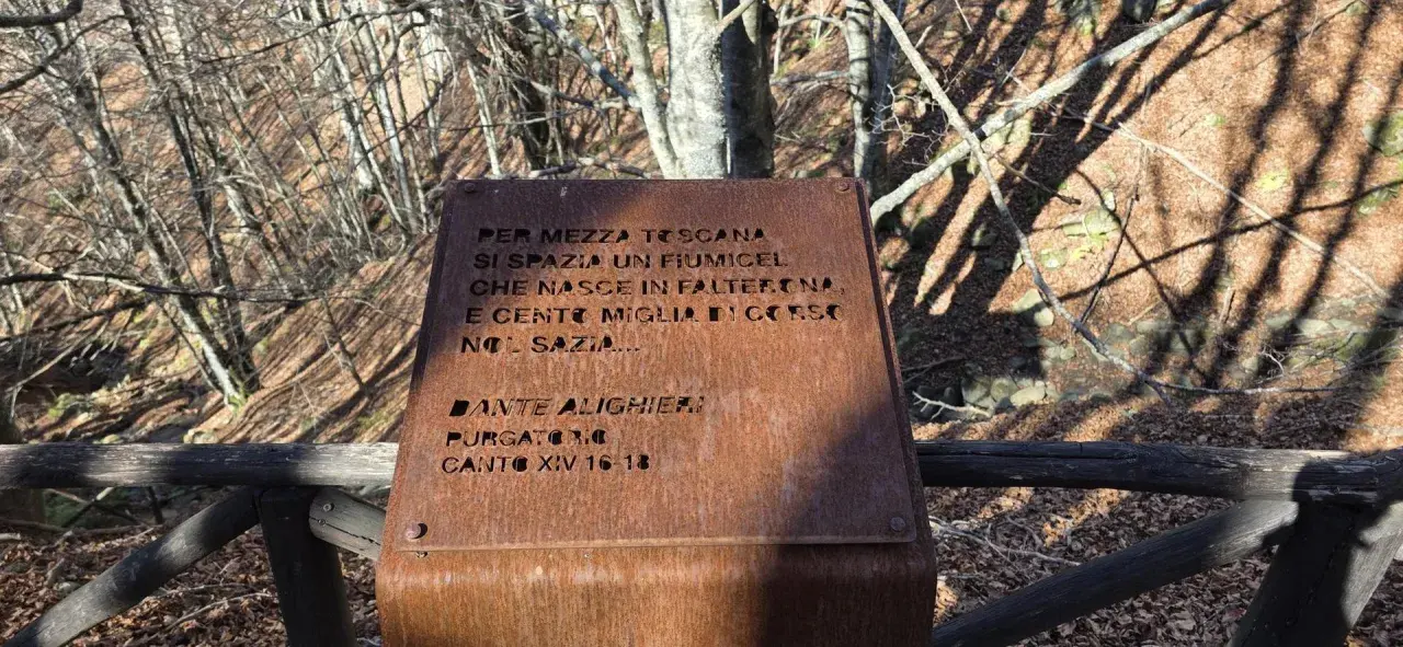 Targa arrugginita sul monte Falterona con citazione di Dante Alighieri sul fiume che nasce qui.