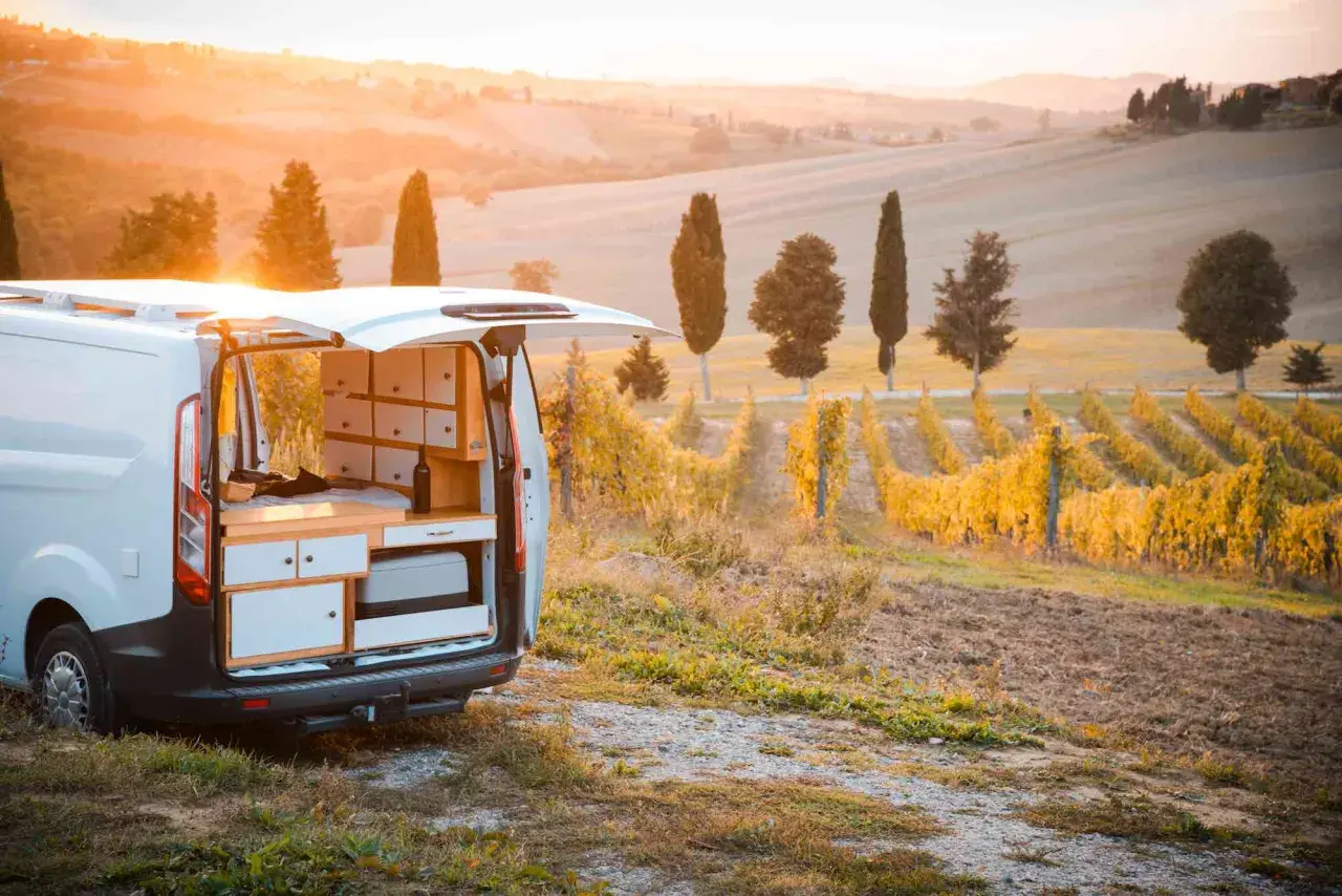 Un furgone camper attrezzato in un vigneto al tramonto, perfetto per un'avventura di **Toscana in camper 3 giorni**.