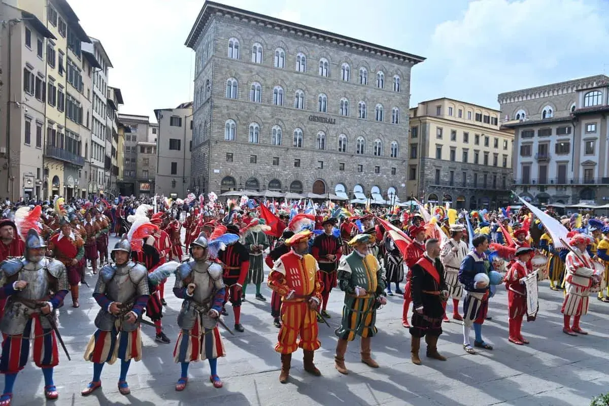 Sfilata storica a San Giovanni, Firenze. Uomini in costume rinascimentale, con armature e bandiere, celebrano la festa.