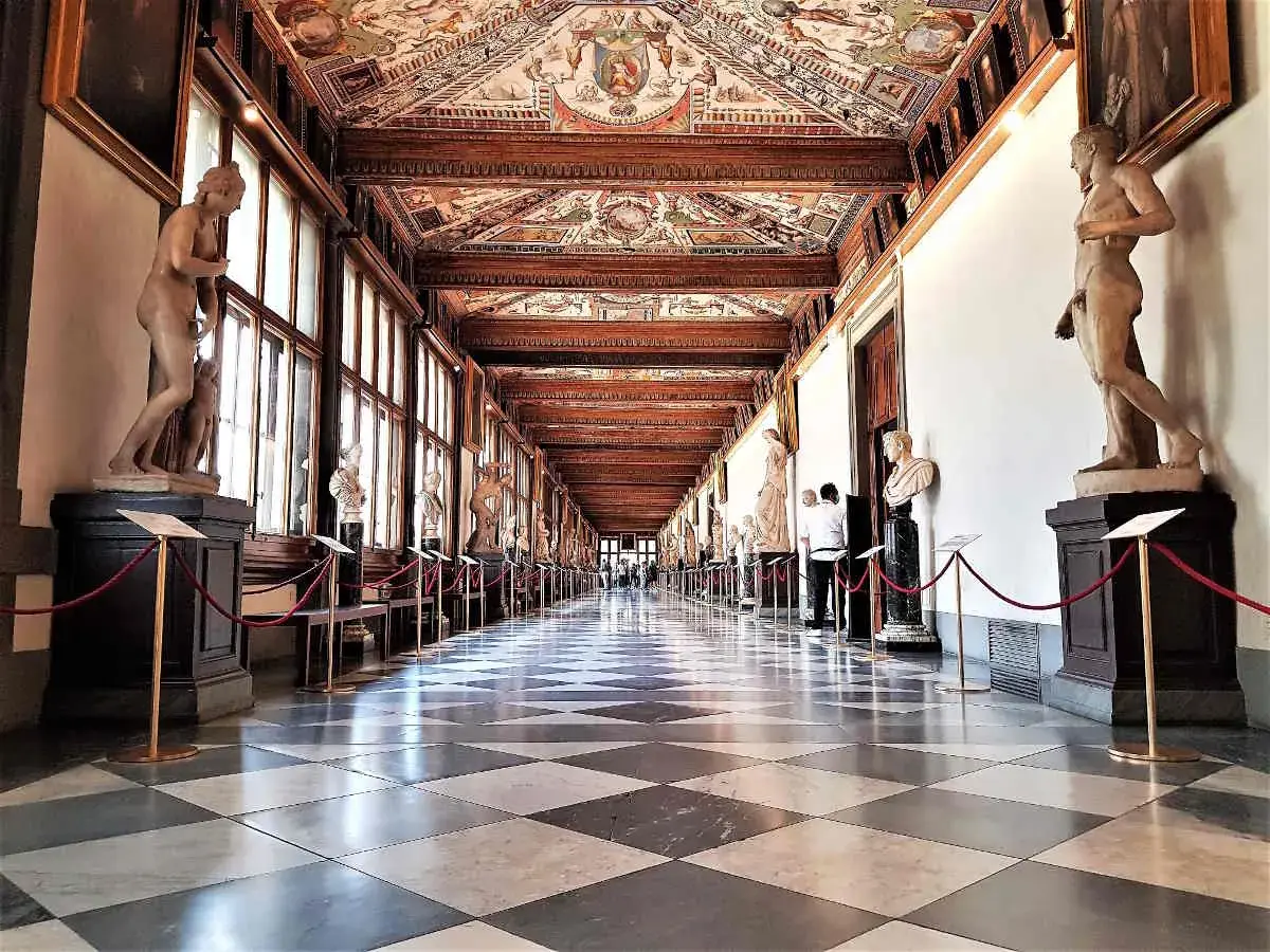 Corridoio degli Uffizi con statue classiche e soffitto affrescato. Un assaggio di cosa vedere agli Uffizi, tra capolavori e architettura.