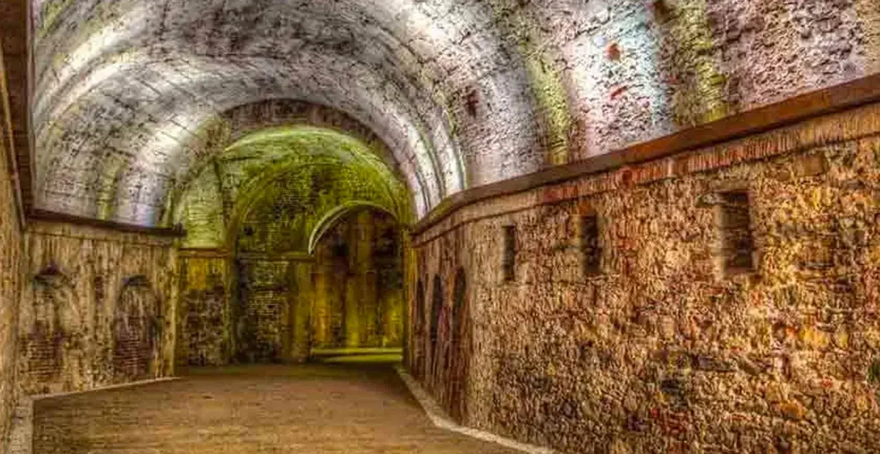 Antiche volte e mura in pietra di una domus romana a Lucca, illuminate da luci soffuse che creano un'atmosfera suggestiva.