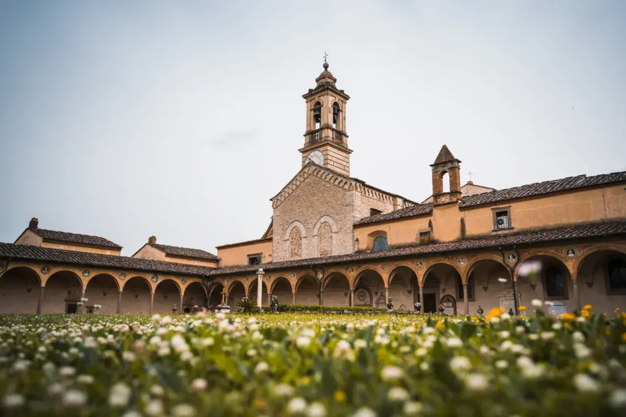 Cortile con portico ad archi e campanile, immerso in un prato fiorito. Un luogo sereno sul monte Senario.