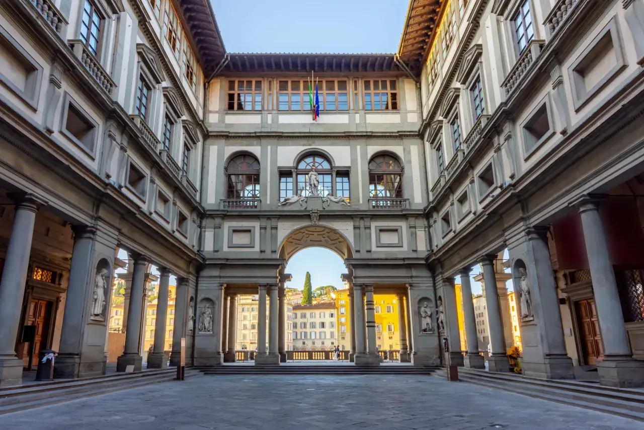 Cortile degli Uffizi, uno dei principali musei da vedere a Firenze. Architettura rinascimentale con statue e un arco che si apre sulla città.