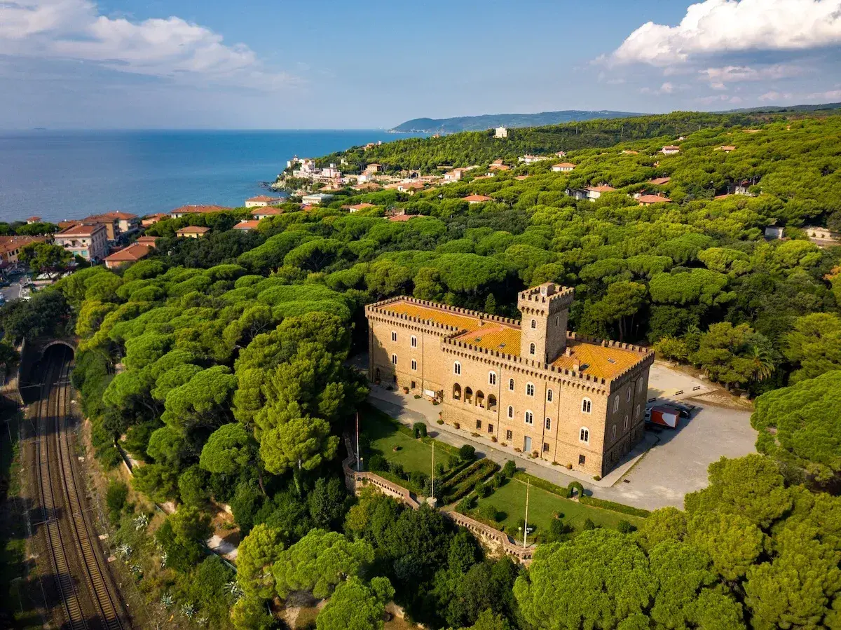 Castiglioncello cosa vedere: un castello imponente circondato da una pineta rigogliosa, con il mare all'orizzonte.