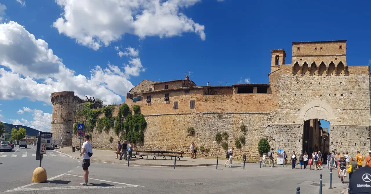 La **Siena Fortezza Medicea** domina il paesaggio con le sue mura imponenti. Turisti passeggiano sotto il sole, ammirando la storia.