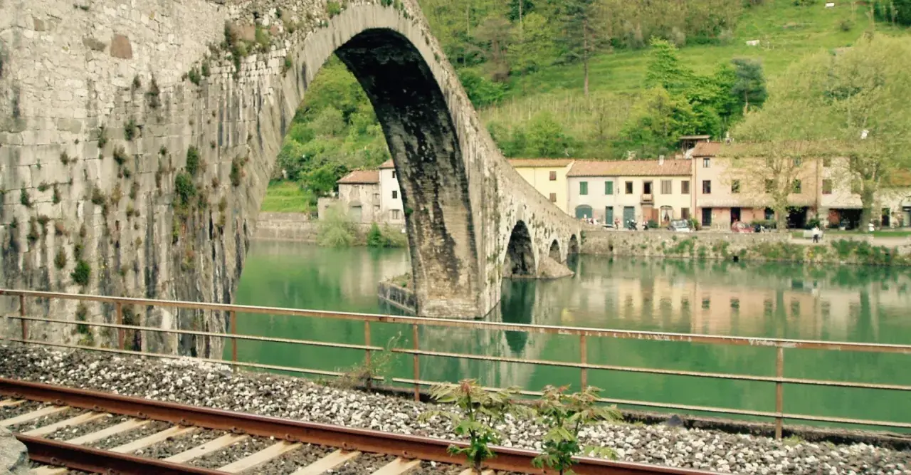 Ponte del Diavolo a Borgo a Mozzano, con case colorate e il fiume Serchio.