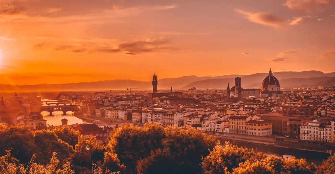 Un tramonto infuocato illumina il panorama di Firenze, con il Duomo e Ponte Vecchio che emergono tra gli edifici. Un'emozione da vedere a Firenze.