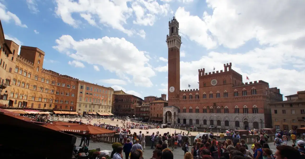 Piazza del Campo a Siena, con la Torre del Mangia e i suoi monumenti, animata da turisti.