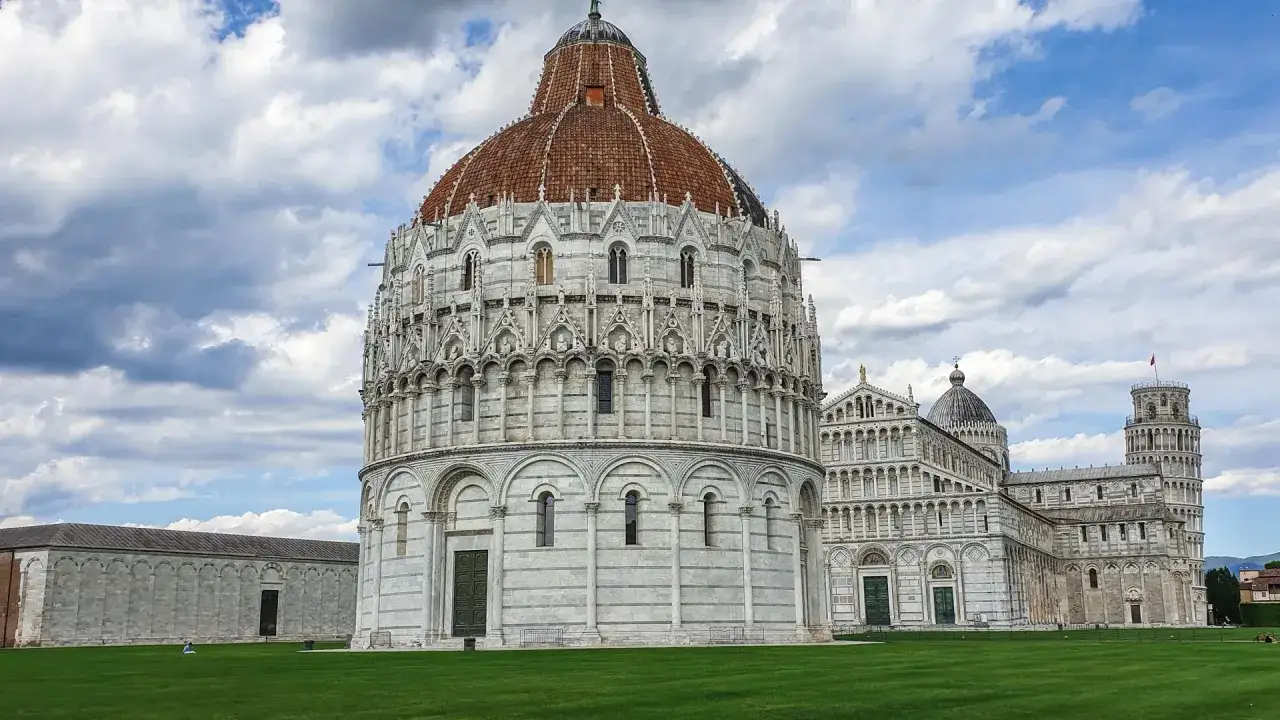 Pisa cosa vedere: il Battistero, il Duomo e la Torre Pendente, capolavori romanici su un prato verde.