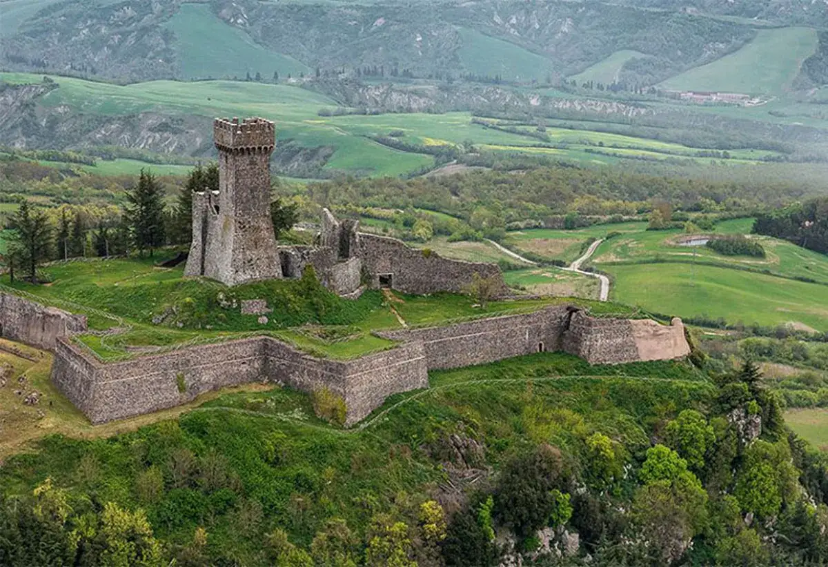 La fortezza di Radicofani domina un paesaggio collinare verdeggiante, con mura antiche e una torre imponente che raccontano storie di secoli passati.