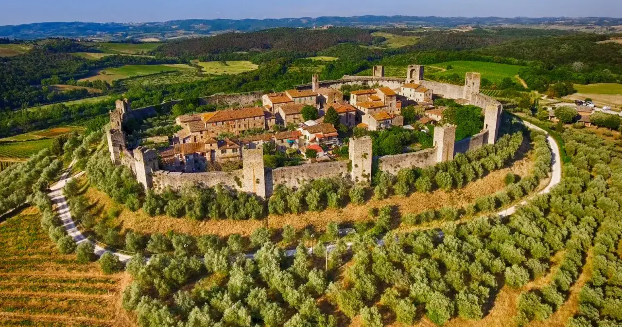 Un borgo medievale fortificato su una collina, circondato da ulivi e vigneti. Ecco cosa vedere a Monteriggioni, un gioiello toscano.