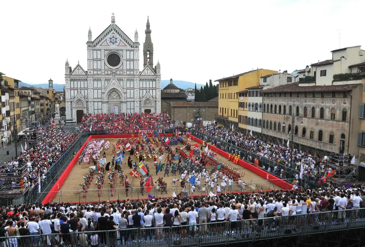 Battaglia di uomini in costume con bandiere e stendardi durante il calcio storico firenze, con la Basilica di Santa Maria Novella sullo sfondo.
