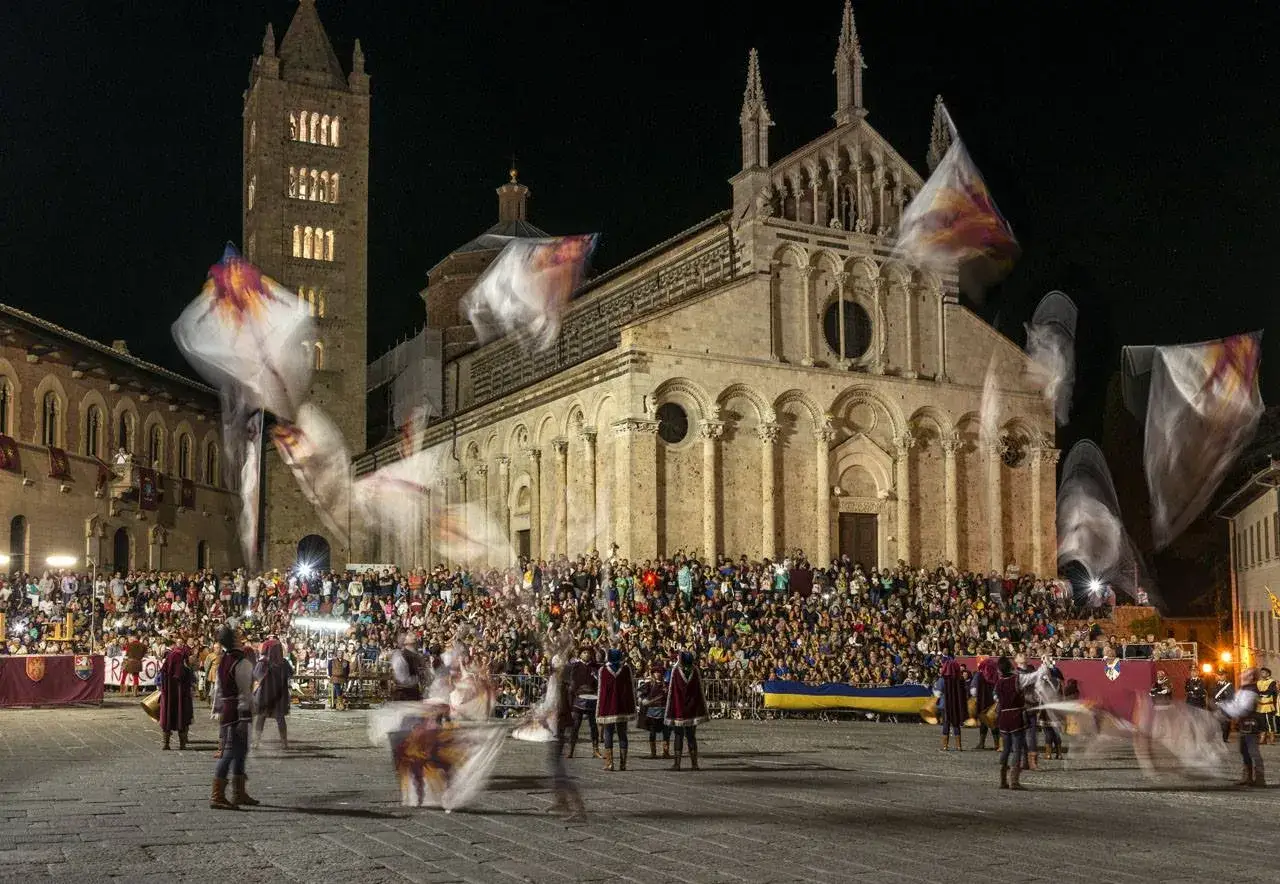 Sbandieratori in azione davanti a una cattedrale illuminata, un'esibizione che ricorda il balestro del girifalco.