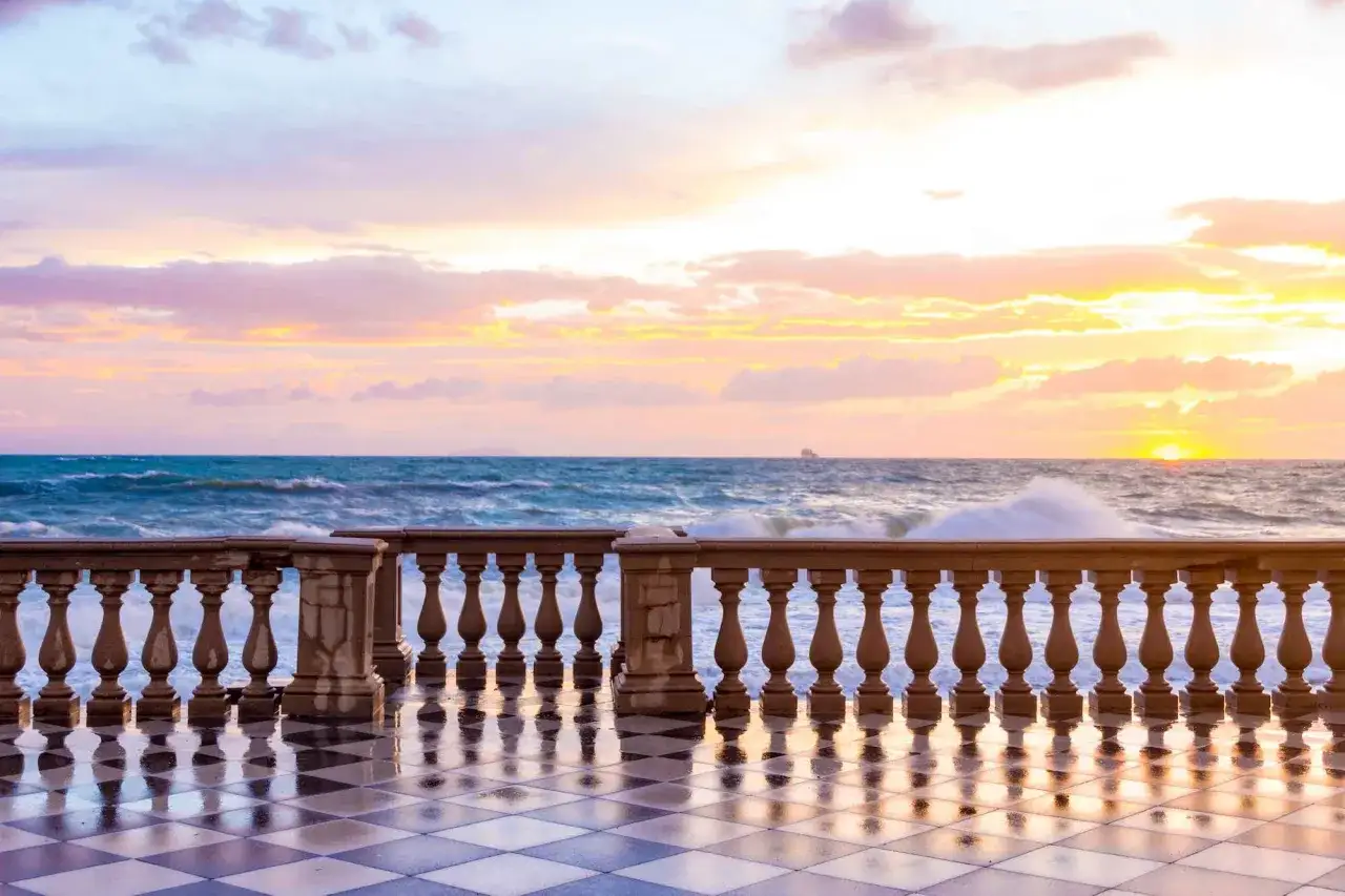 Tramonto sulla terrazza Mascagni a Livorno, con il mare in tempesta e un cielo dai colori pastello.