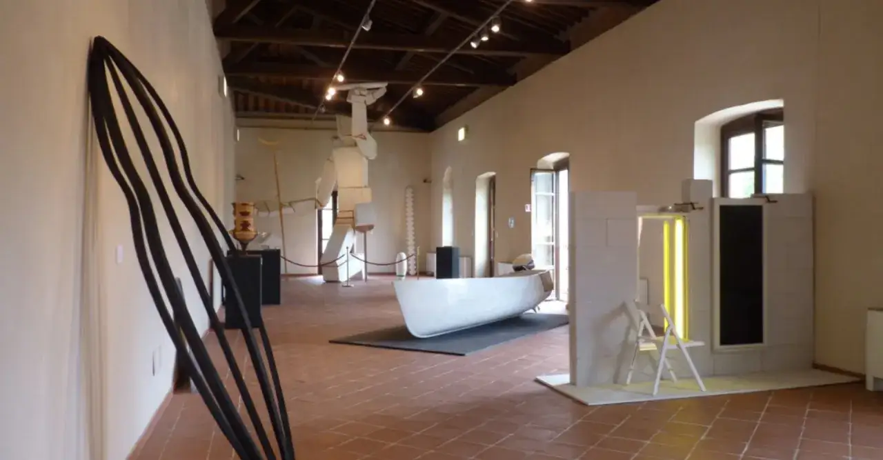 Interno del mudac carrara con sculture moderne, tra cui una barca bianca e un'installazione a parete nera.