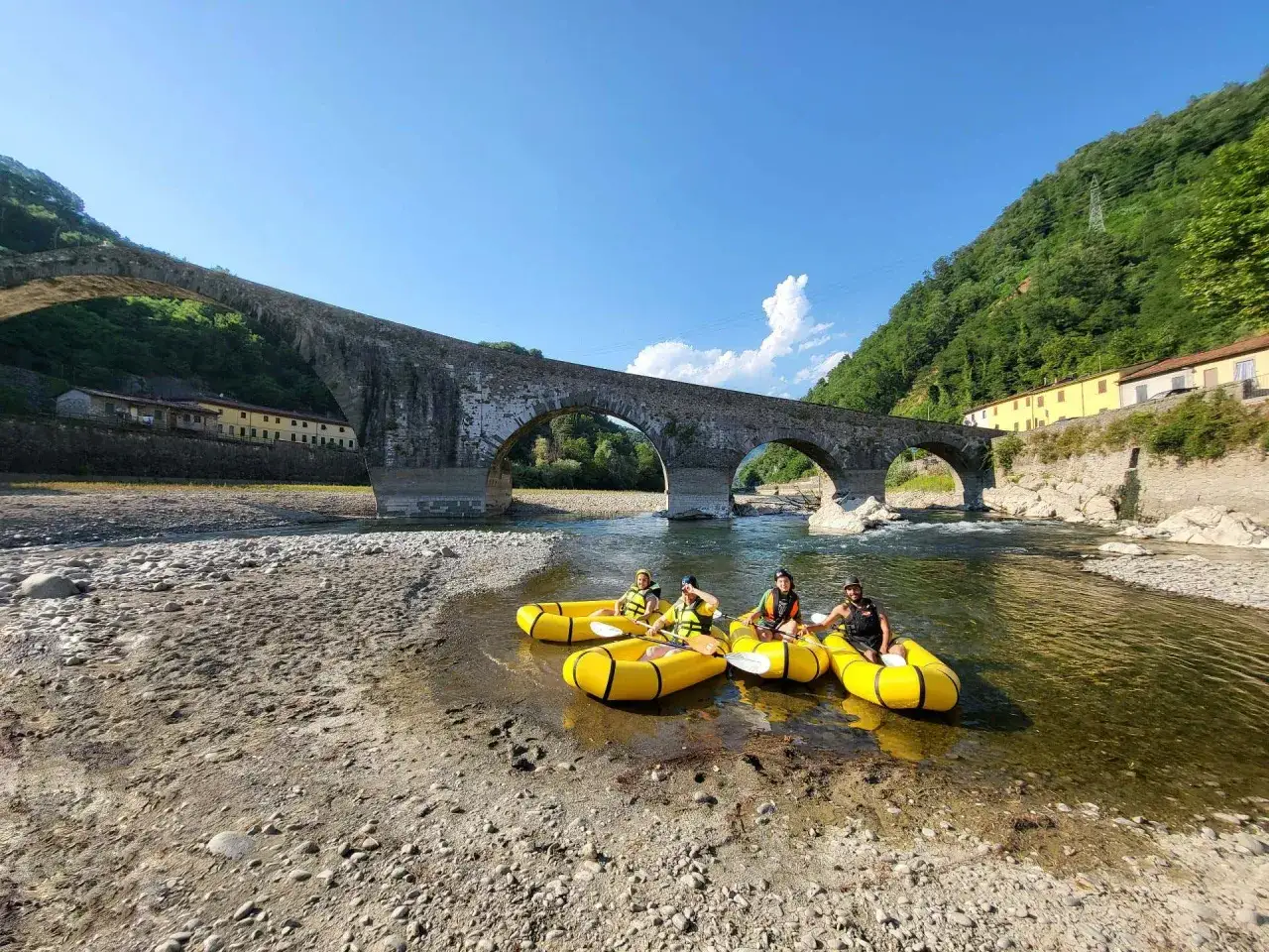 Gente in kayak gialli sul fiume Serchio, sotto il Ponte del Diavolo, nel parco fluviale del Serchio.