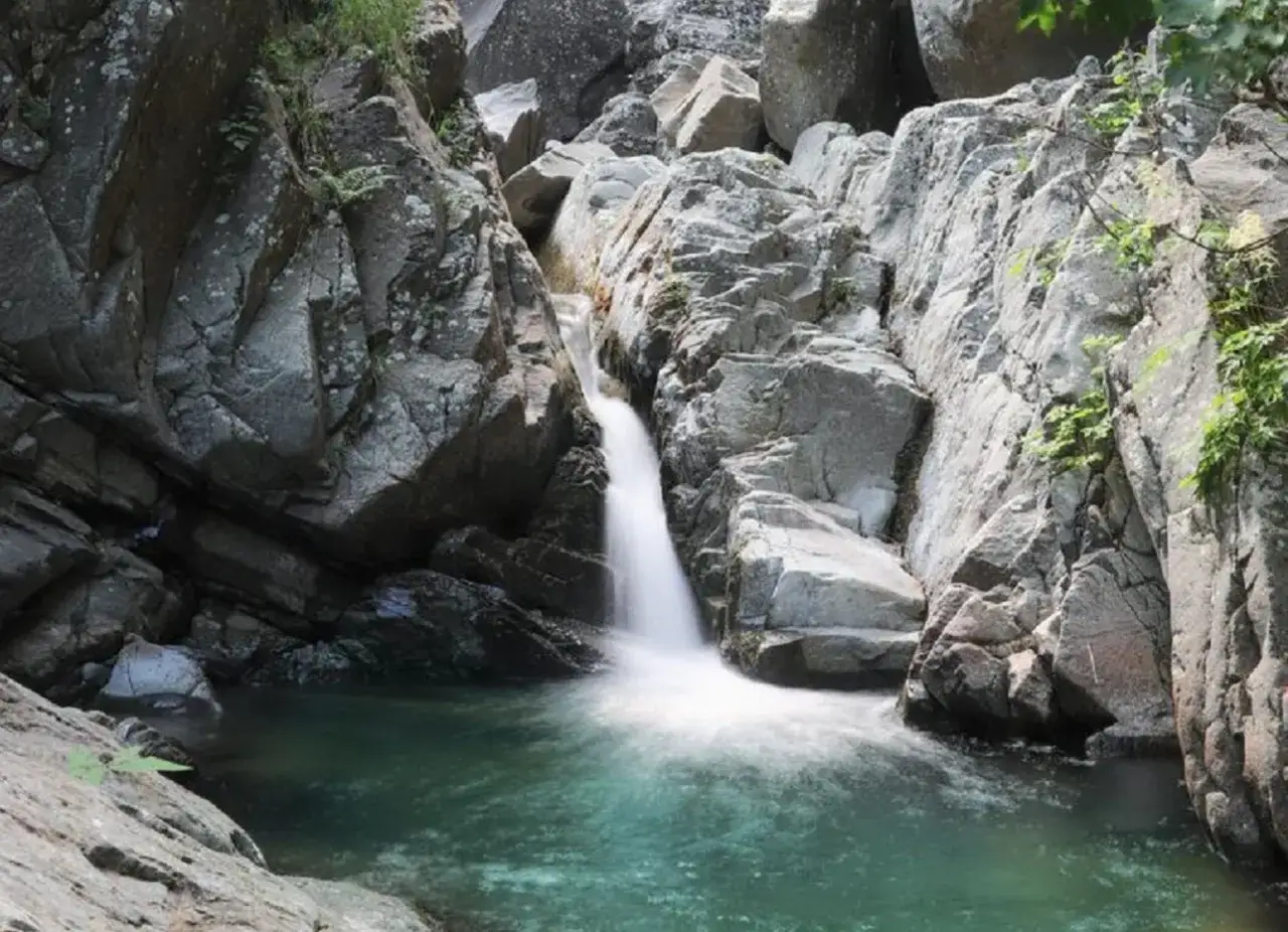 Cascate naturali vicino a Pontremoli, con acqua cristallina che scende tra rocce grigie e vegetazione rigogliosa.