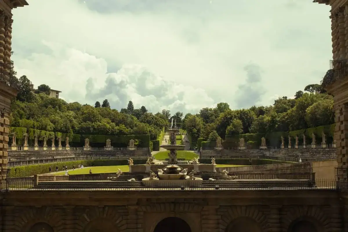 Magnifico giardino di Boboli con fontane, statue e verde rigoglioso, sotto un cielo nuvoloso.