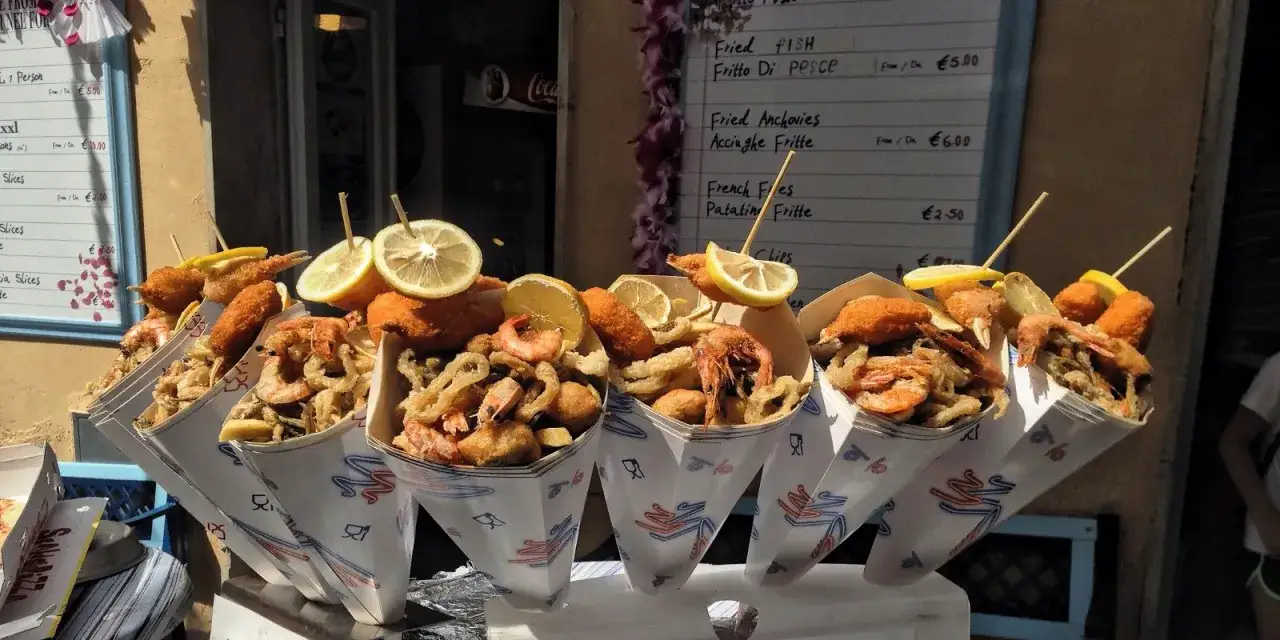 Coni di fritto misto di pesce e patatine, un'esplosione di sapori al poggibonsi markt, guarniti con spicchi di limone.