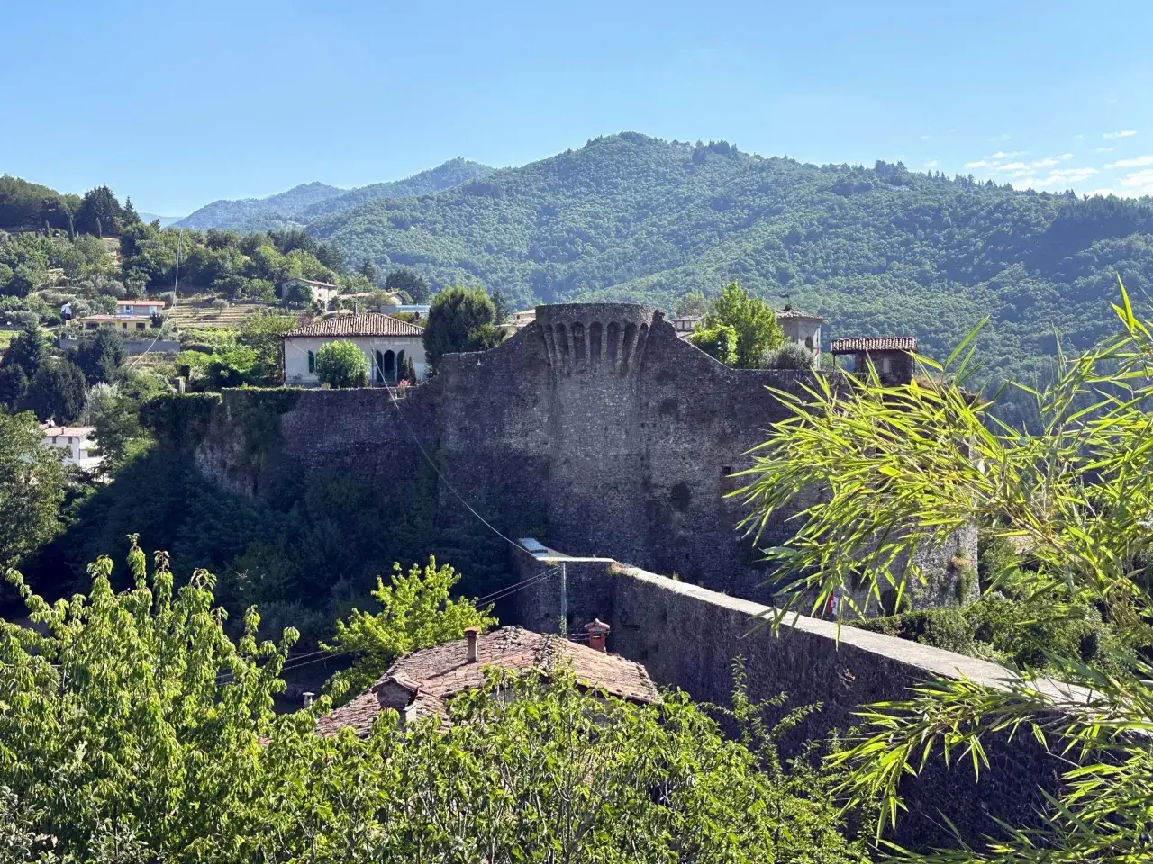 La rocca di Castiglione domina il paesaggio collinare, con le sue mura antiche e le case sui pendii verdi.