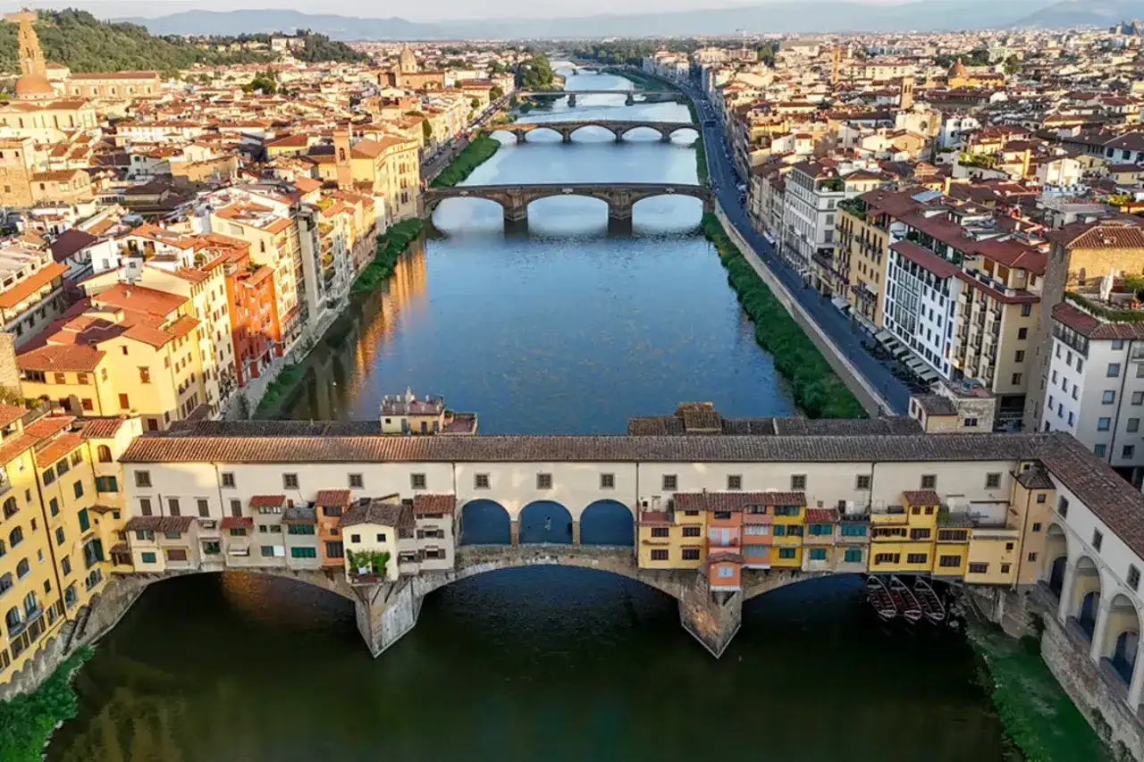 Un giorno a Firenze, il Ponte Vecchio con le sue botteghe colorate si specchia sull'Arno, mentre altri ponti attraversano la citt&agrave;.