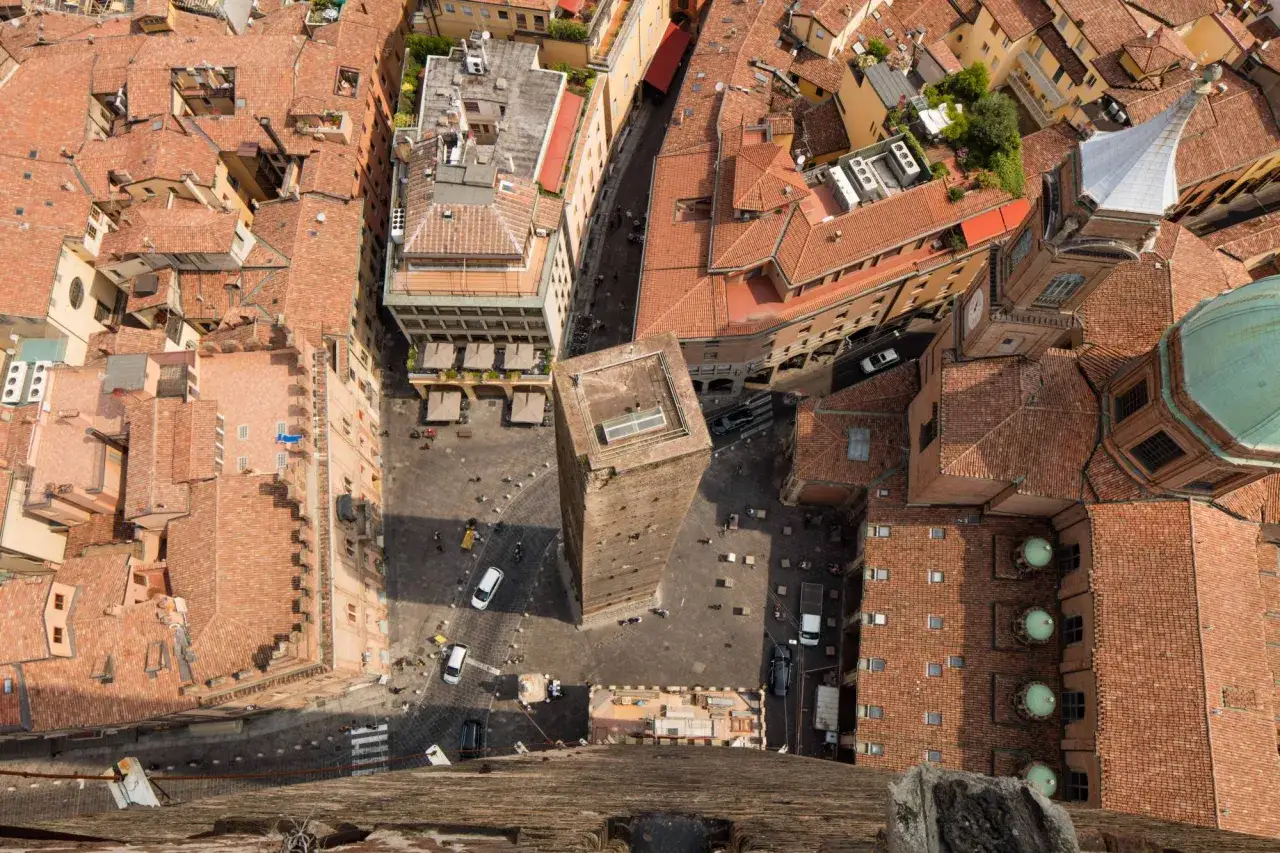 Vista aerea di Bologna con la torre degli Asinelli che domina la piazza e i tetti rossi della città.