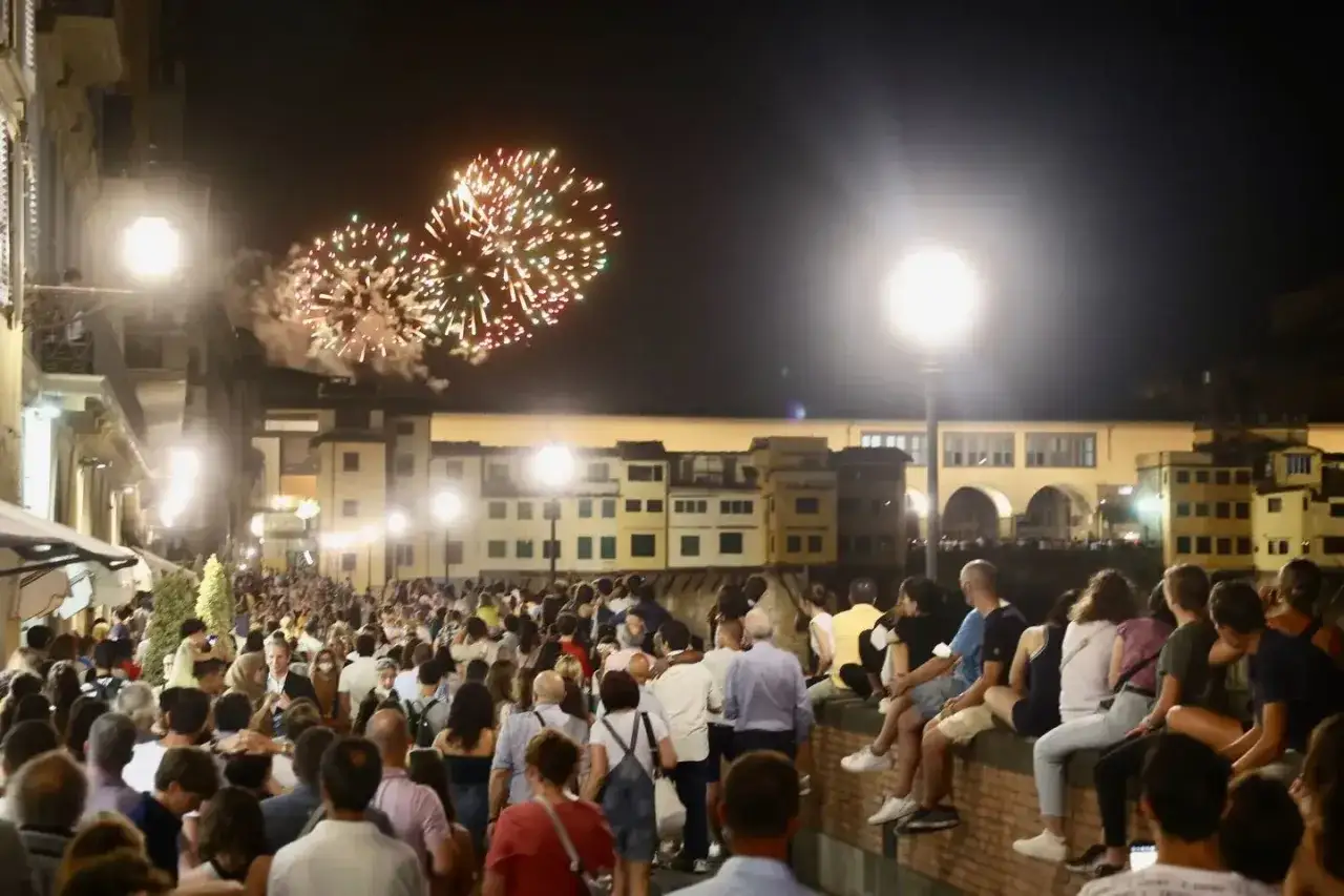 Fuochi d'artificio illuminano il cielo notturno sopra una folla festante a San Giovanni, Firenze.